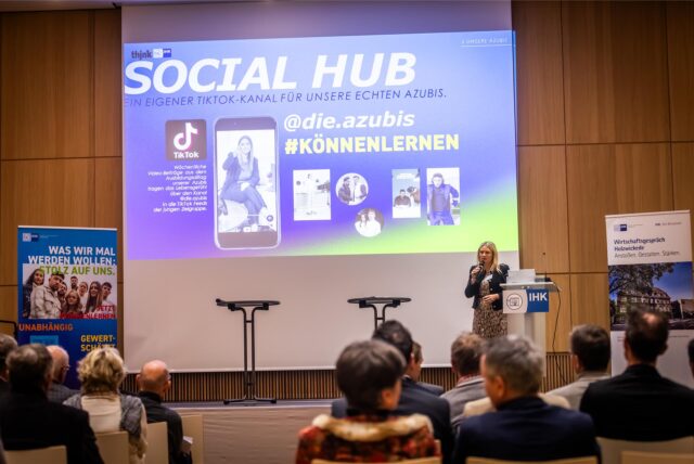 Eine Rednerin der IHK zu Dortmund steht im Emschersaal des Holzwickeder Rat- und Bürgerhauses vor Publikum am Mikrofon.