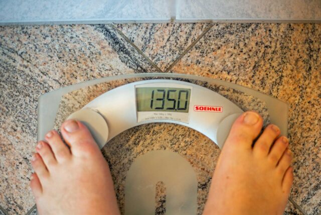 Ein Mensch steht auf einer Waage, die den Wert von 135 Kilogramm zeigt.