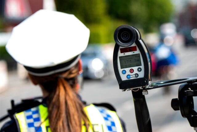 Eine Polizistin kontrolliert die Geschwindigkeit von Autos mit einem Messgerät