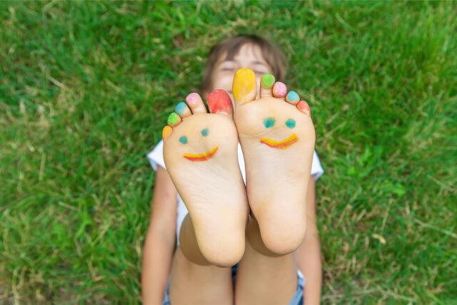 Mit lächelndem Gesicht bemalte Kinderfüße.