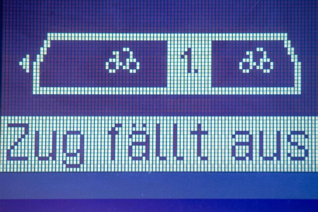 Eine blau-weiße elektronische Anzeige der Deutsche Bahn. Es ist das Fahrradabteil und das Abteil der ersten Klasse zu sehen und der Schriftzug „Zug fällt aus“ ist darauf zu lesen.