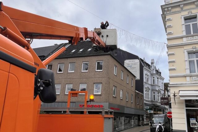 Von einer Hebebühne aus befestigt ein Mann eine Lichterkette am Markt in Unna