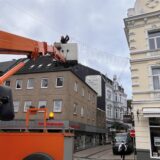 Von einer Hebebühne aus befestigt ein Mann eine Lichterkette am Markt in Unna