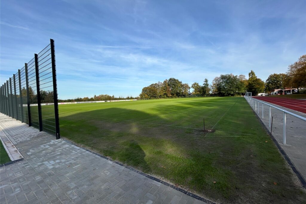 Ein Fußballplatz mit Bäumen im Hintergrund. Daneben ist eine Laufbahn Ein Fußballplatz mit Bäumen im Hintergrund. Daneben ist eine Laufbahn