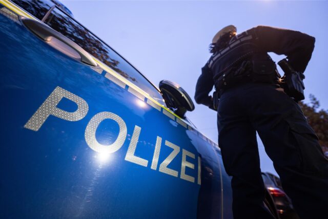 Eine Polizistin steht neben einem Streifenwagen der Polizei.