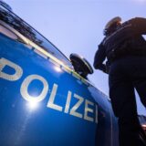 Eine Polizistin steht neben einem Streifenwagen der Polizei.
