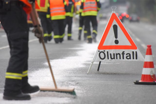 Ein Feuerwehrmann beseitigt eine Ölspur.