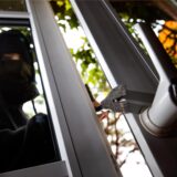 Ein Einbrecher hebelt in einer gestellten Szene ein Fenster mit einer Brechstange auf