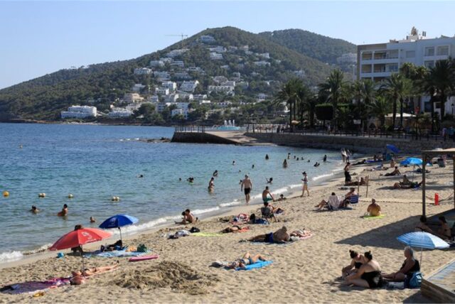 Menschen sonnen sich am Strand von Santa Eulalia auf Ibiza.