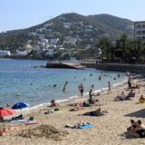 Menschen sonnen sich am Strand von Santa Eulalia auf Ibiza.