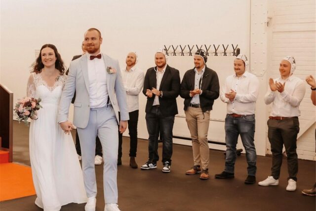Ein Ehepaar schreitet nach seiner Hochzeit durch ein Spalier seiner Freunde.