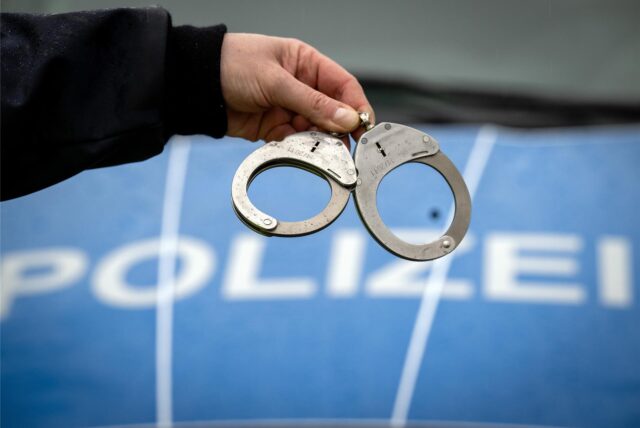 Ein Polizist zeigt Handschellen.
