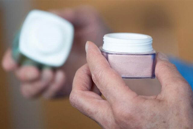 Eine Person hält einen Creme-Tiegel in der Hand.