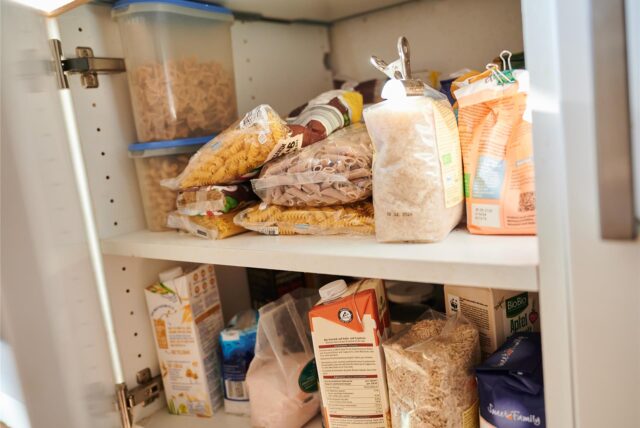 In einem Küchenschrank liegen Vorräte. Nudeln, Zucker, Mehl, Milch und Salz unterschiedlicher Hersteller sind zu sehen.