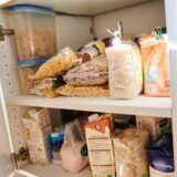 In einem Küchenschrank liegen Vorräte. Nudeln, Zucker, Mehl, Milch und Salz unterschiedlicher Hersteller sind zu sehen.