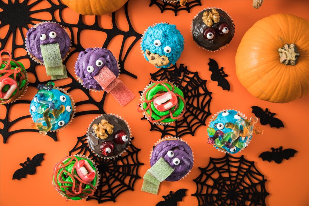 Da können sich kleine Halloweenjünger schon im Vorfeld der Party kreativ austoben: Mit Frischkäse-Frosting, Lebensmittelfarben und Zuckerdekor lassen sich putzige Monster-Muffins zubereiten.