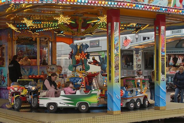 Am Eröffnungstag der Katharinenkirmes in Unna halten eine Frau und zwei Kinder in Halloween-Kostümen Lebkuchenherzen in den Händen.
