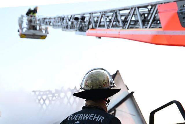 Ein Feuerwehrmann steht bei einem Einsatz bei einem Brand an einer Drehleiter. (Symbolbild)
