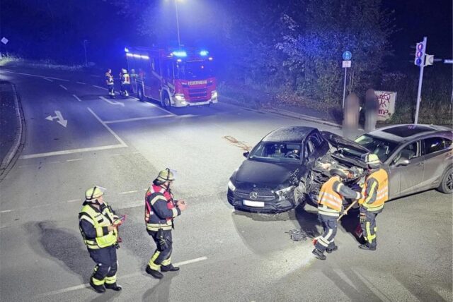 Auf dem Bild sieht man einen Unfall, bei dem zwei Autos zusammengestoßen sind. Die Feuerwehr ist vor Ort mit einem Löschwagen.