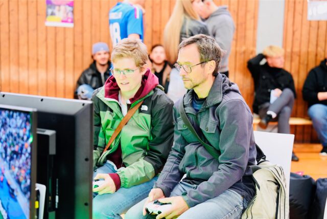 Zwei Besucher des F4 Gaming-Festivals 2024 in Schwerte sitzen an einer Konsole.