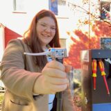 Ruhr Nachrichten-Praktikantin Megan Grudniok hält einen Pumpschlauch der neuen Radservice-Säule in Schwerte in der Hand. Die Bike-Repair-Station steht „Im Reiche des Wassers“.