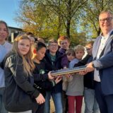 Aschebergs Bürgermeister Thomas Stohldreier und Schüler halten eine Zeitkapsel.