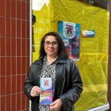 Monica Urquiola-Abdinghoff hält einen Flyer ihres Unternehmens in Händen.