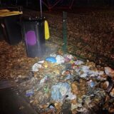 Ausgebrannter Unrat, Lichtkegel erhellt Bereich um eine Mülltonne.