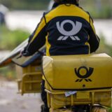 Eine Briefträgerin auf einem Fahrrad.