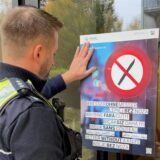 Ein Polizeibeamter hängt in Dortmund ein Plakat der Aktion „Besser ohne Messer“ auf.