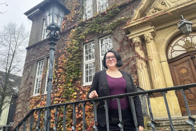 Annika Lomberg steht vor dem Rat- und Bürgerhaus und einer herbstlichen Bepflanzung.