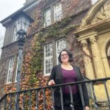 Annika Lomberg steht vor dem Rat- und Bürgerhaus und einer herbstlichen Bepflanzung.