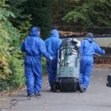 Arbeiter in Overalls ziehen ein Reinigungsgerät zu einem Grundstück.