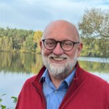 Dr. Hubert Seier, Mitglied des Kreistags Unna, aus Selm, steht vor einem See.