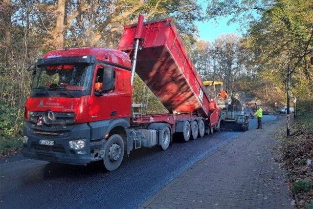 Auf eine Holzwickeder Straße wird eine neue Asphaltschicht aufgetragen.