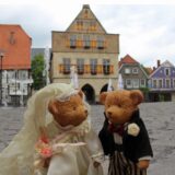 Ein Teddy-Hochzeitspaar steht auf dem Marktplatz von Werne, im Hintergrund ist das Rathaus zu sehen.