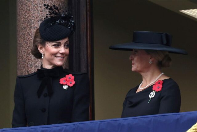 Prinzessin Kate (links) und Herzogin Sophie (rechts), in Schwarz gekleidet, mit Hüten und roten Ansteckern.