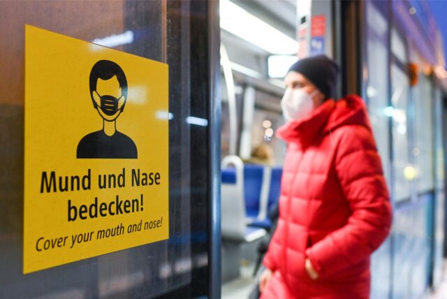 Eine Frau steigt mit FFP2-Maske in eine Trambahn ein.