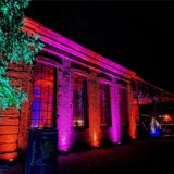 Hertens Orangerie im Schlosspark bei Nacht, hier in den Lichtfarben Rot und Lila illuminiert.