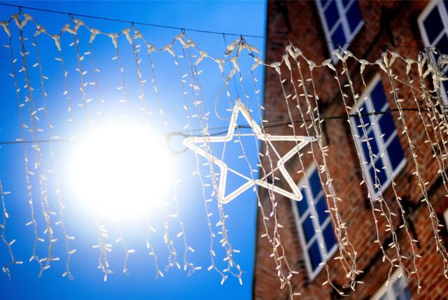 Die noch nicht eingeschaltete Weihnachtsbeleuchtung hängt in der Innenstadt vor einer leuchtenden Straßenlaterne.
