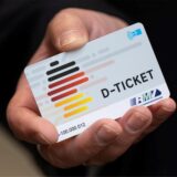 Eine Hand hält ein Deutschlandticket.