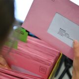 Umschläge mit Wahlunterlagen werden in einem Briefwahlbüro sortiert.