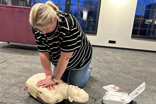 Frau zeigt Herzdruck-Massage an einer Puppe