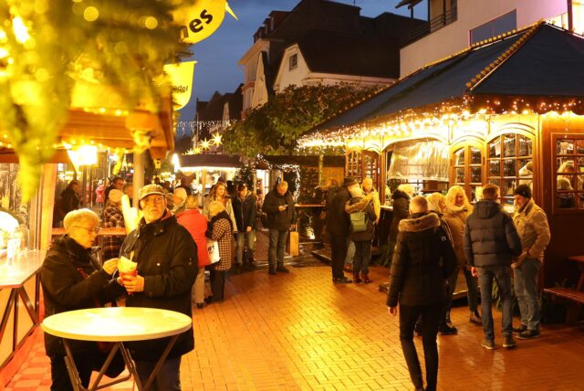 Besucher gehen abends durch die erleuchtete Sternengasse auf dem Weihnachtsmarkt in Lünen 2022.