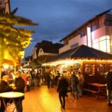 Besucher gehen abends durch die erleuchtete Sternengasse auf dem Weihnachtsmarkt in Lünen 2022.