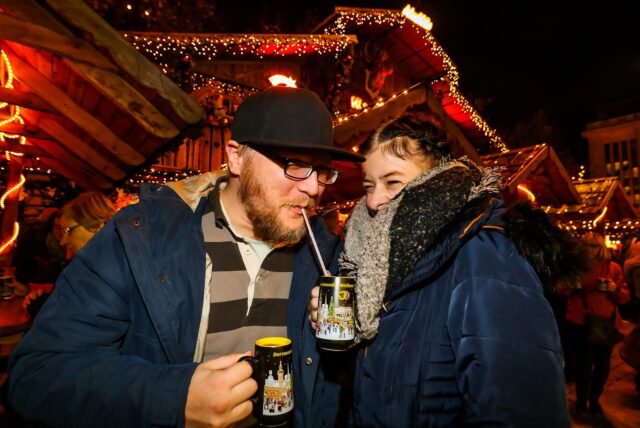 Zwei Besucher des Dortmunder Weihnachtsmarktes trinken Glühwein und Lumumba aus der speziellen Dortmunder Weihnachtsmarkt-Tasse.