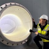 Bernd Heinz (Geschäftsführer von Wasserwerke Westfalen) steht mit einer Taschenlampe vor dem Zwischenspeicher im Rohbau des Wasserwerks Halingen und leuchtet hinein.
