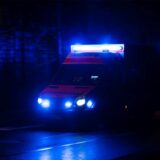 Ein Krankenwagen fährt mit Blaulicht durch eine Straße in der Nacht.