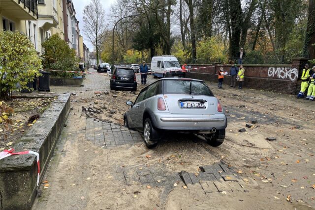 Ein Auto steht nach einem Wasserrohrbruch in Dortmund in einem Loch.