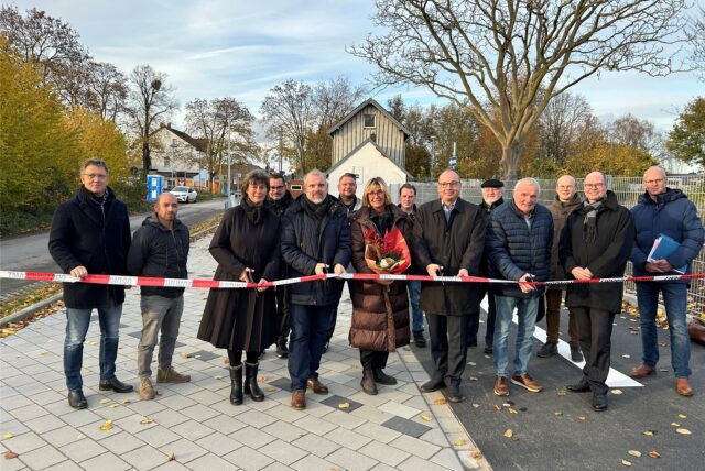 Mehrere Menschen darunter Unnas Bürgermeister Dirk Wigant stehen hinter einem Absperrband auf dem neuen Parkplatz am Bahnhof Lünern